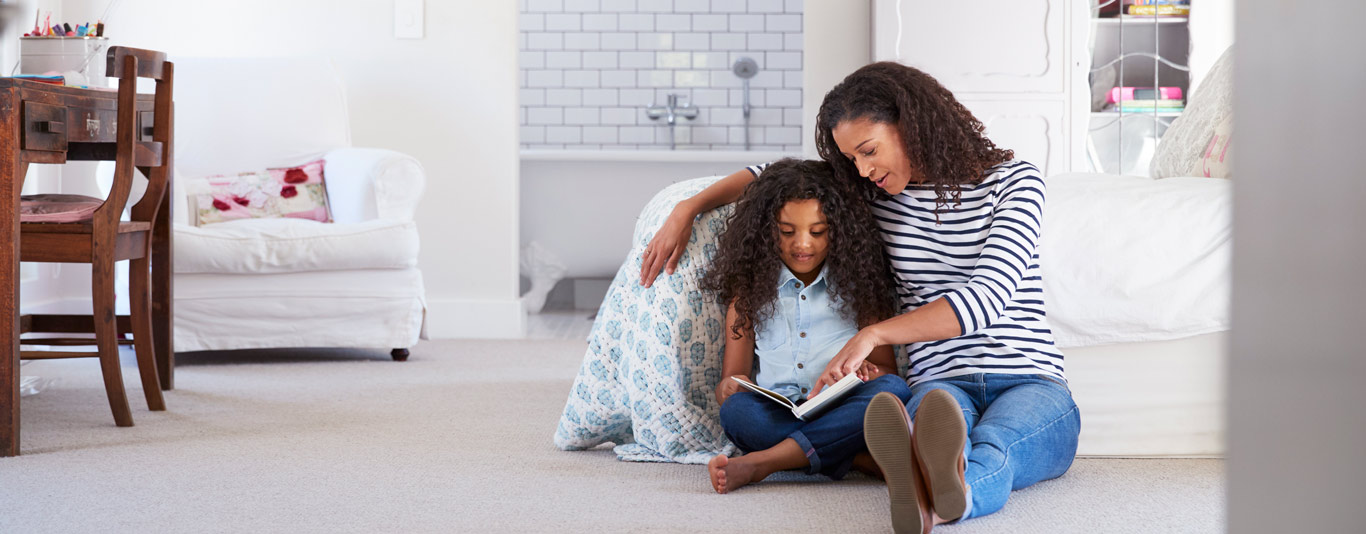 Mom and daughter sitting on the floor reading a book Mom and daughter sitting on the floor reading a book